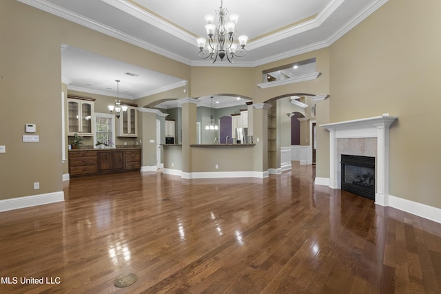 5578 E Diamondhead Dr, Diamondhead, MS 39525 - unfurnished living room featuring arched walkways, a chandelier, dark wood-style floors, ornate columns, and ornamental molding