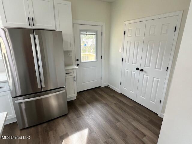 kitchen with stainless steel refrigerator, dark wood-type flooring, and white cabinets