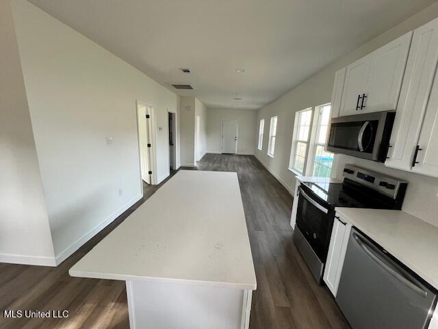 kitchen featuring white cabinetry, stainless steel appliances, dark hardwood / wood-style flooring, and a kitchen island