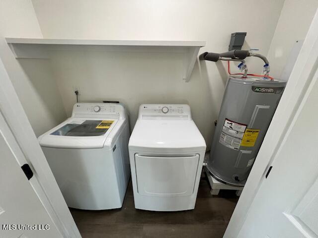 laundry room with dark hardwood / wood-style floors, electric water heater, and washer and dryer