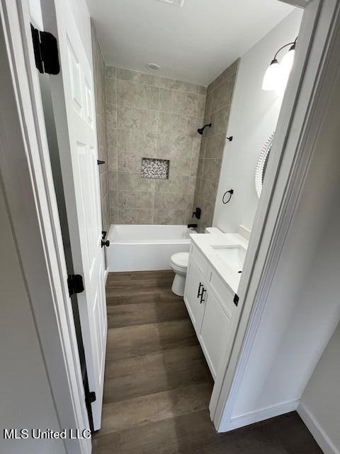 full bathroom featuring vanity, tiled shower / bath, hardwood / wood-style flooring, and toilet