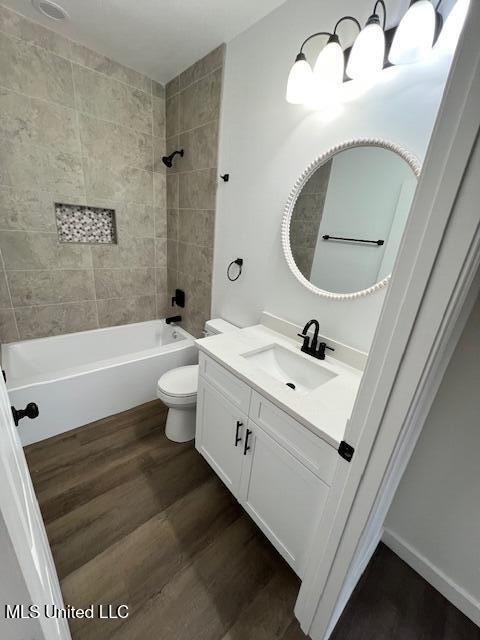 full bathroom with vanity, hardwood / wood-style flooring, toilet, and tiled shower / bath combo