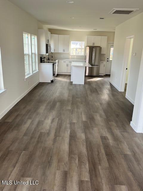 kitchen with appliances with stainless steel finishes, a center island, white cabinets, and dark hardwood / wood-style flooring