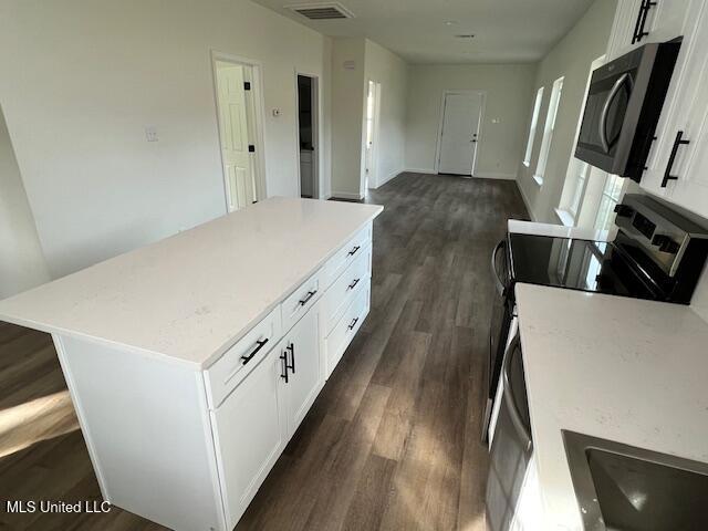 kitchen featuring white cabinetry, a kitchen island, and stainless steel electric range