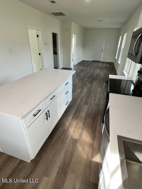 kitchen with white cabinetry, a kitchen island, electric range, and dark hardwood / wood-style flooring