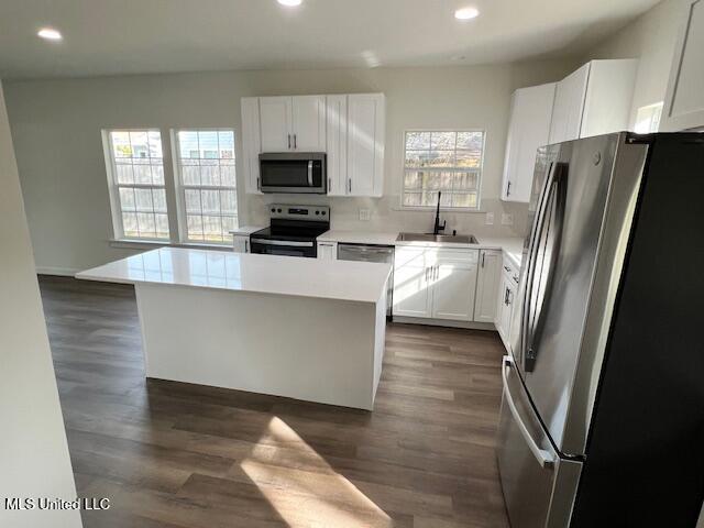 kitchen with sink, stainless steel appliances, dark hardwood / wood-style floors, white cabinets, and a kitchen island