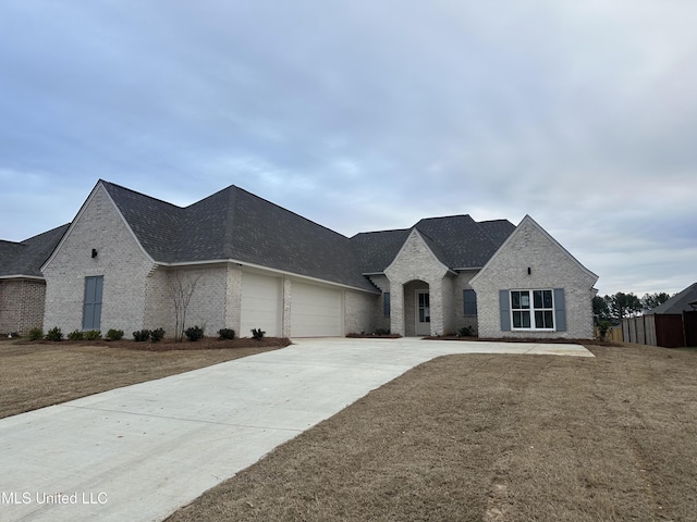 french country home featuring a garage and a front lawn