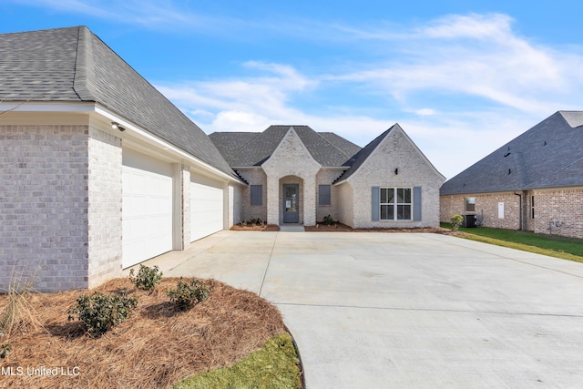 french provincial home featuring a garage and cooling unit