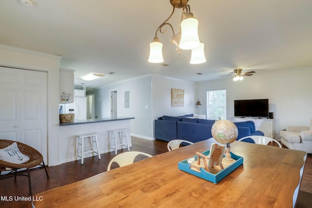 dining space with electric panel, baseboards, dark wood finished floors, ceiling fan, and crown molding