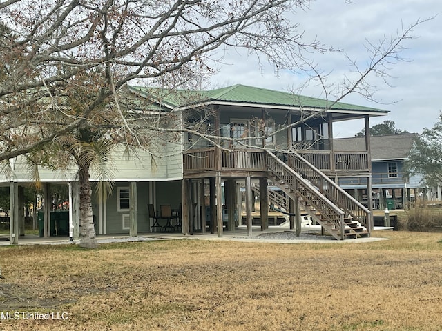 rear view of property with metal roof, stairway, a patio area, and a lawn