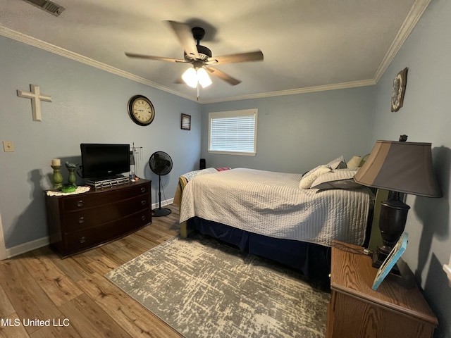 bedroom with baseboards, visible vents, wood finished floors, and ornamental molding