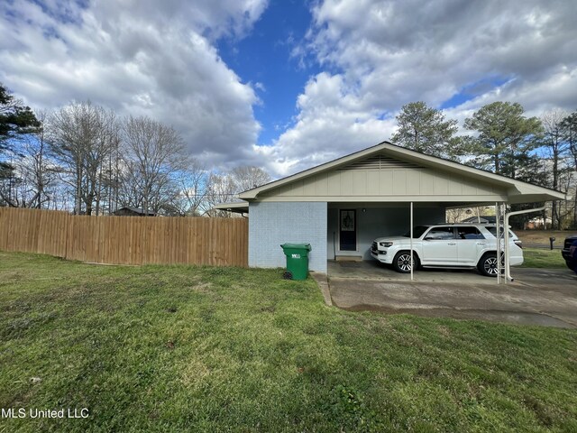 view of property exterior with brick siding, a yard, fence, an attached carport, and driveway