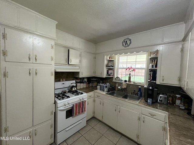 kitchen with light tile patterned floors, gas range gas stove, under cabinet range hood, open shelves, and a sink