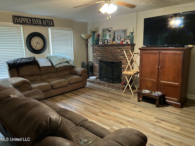 living room with ornamental molding, a brick fireplace, light wood-style floors, and ceiling fan