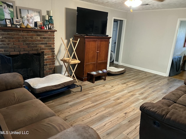 living area with a textured ceiling, a fireplace, wood finished floors, and crown molding