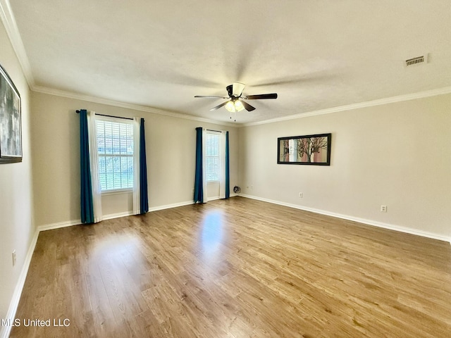 empty room with visible vents, crown molding, baseboards, ceiling fan, and wood finished floors