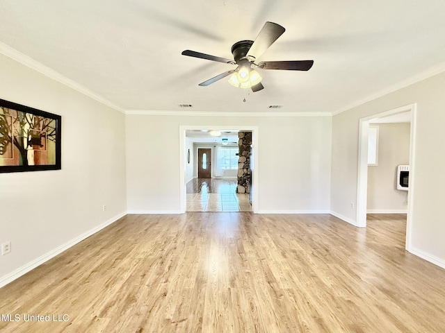 spare room featuring heating unit, wood finished floors, a ceiling fan, baseboards, and crown molding