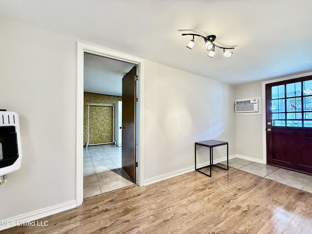 entryway featuring a wall mounted air conditioner, baseboards, heating unit, and wood finished floors