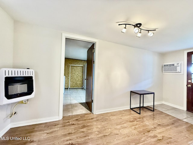 unfurnished dining area featuring baseboards, heating unit, an AC wall unit, and wood finished floors