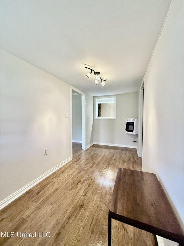 unfurnished living room with baseboards, heating unit, and light wood-style floors