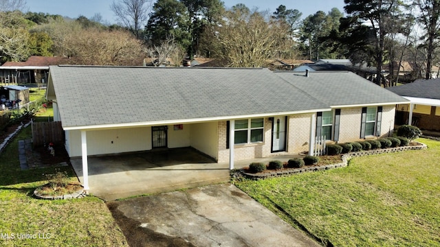 ranch-style house featuring an attached carport, a shingled roof, concrete driveway, a front lawn, and brick siding