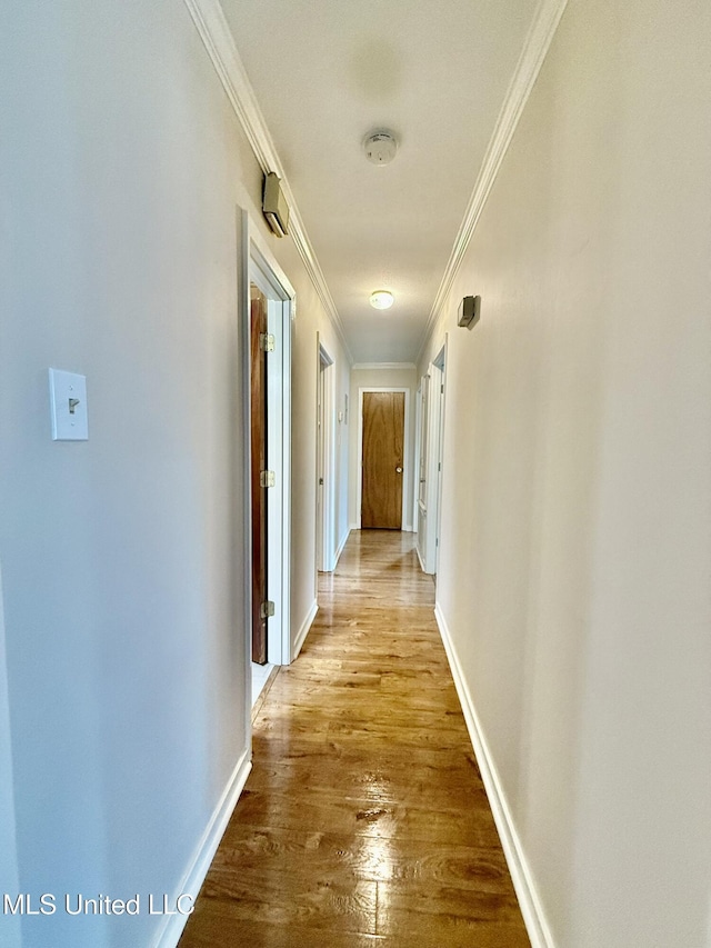 hallway with ornamental molding, baseboards, and wood finished floors