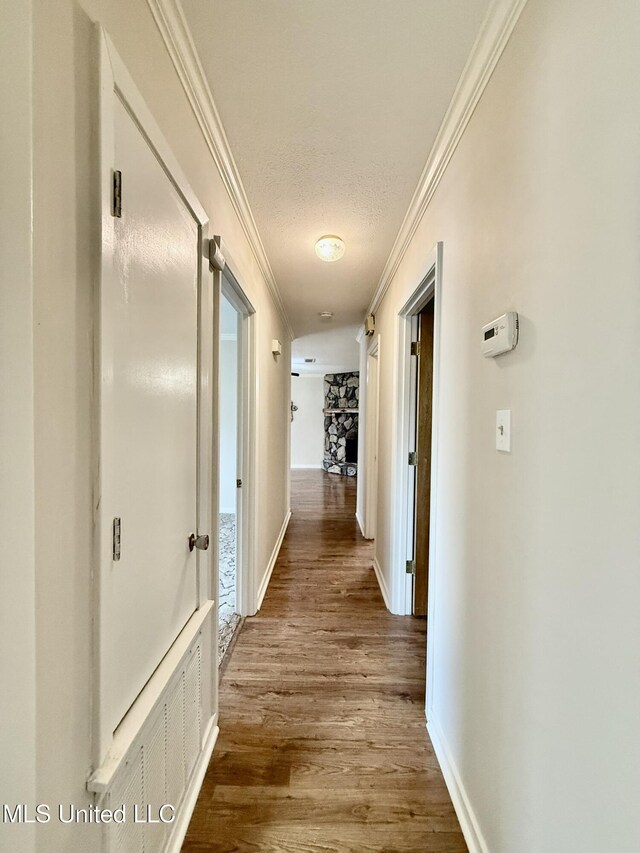 hallway featuring crown molding, wood finished floors, baseboards, and a textured ceiling