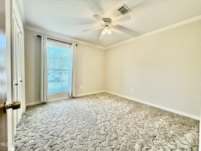 empty room with visible vents, crown molding, baseboards, ceiling fan, and carpet floors