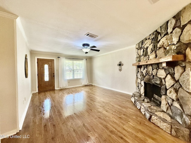 unfurnished living room featuring a fireplace, wood finished floors, visible vents, and ornamental molding