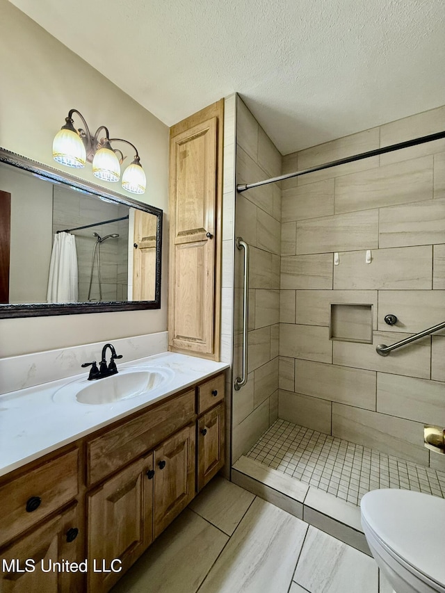 bathroom with toilet, a textured ceiling, tiled shower, and vanity