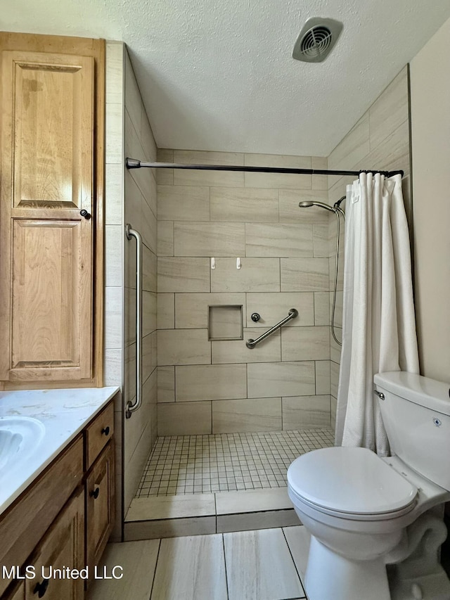 bathroom with vanity, visible vents, a shower stall, a textured ceiling, and toilet