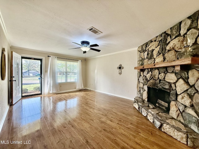 unfurnished living room with ornamental molding, wood finished floors, visible vents, and a textured ceiling