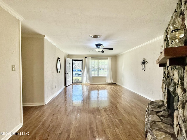 unfurnished living room with visible vents, a textured ceiling, wood finished floors, and crown molding