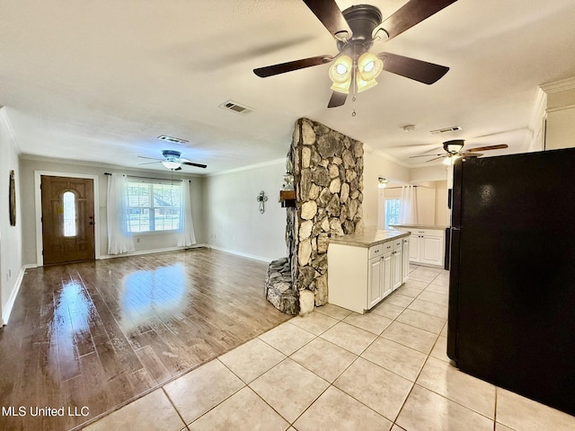 unfurnished living room featuring a ceiling fan, visible vents, and ornamental molding