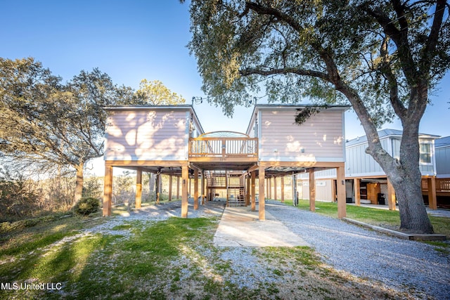 rear view of property with a deck, a lawn, and a carport