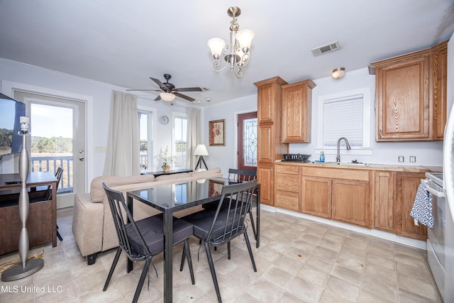 dining room with ceiling fan with notable chandelier, sink, and ornamental molding