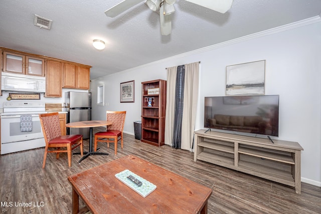 living room featuring ceiling fan, dark hardwood / wood-style flooring, a textured ceiling, and ornamental molding