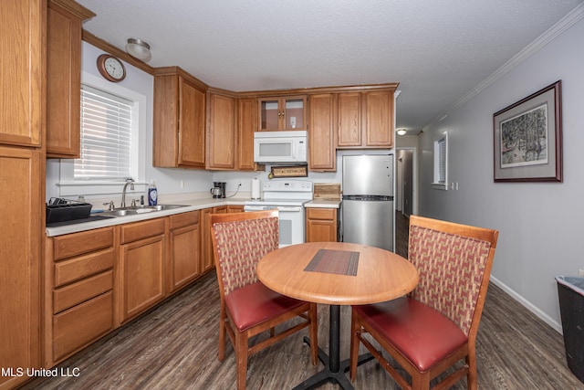 kitchen featuring white appliances, a textured ceiling, dark hardwood / wood-style flooring, sink, and ornamental molding