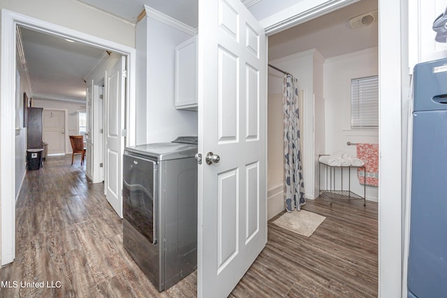 laundry room featuring dark wood-type flooring, cabinets, crown molding, and washer / clothes dryer