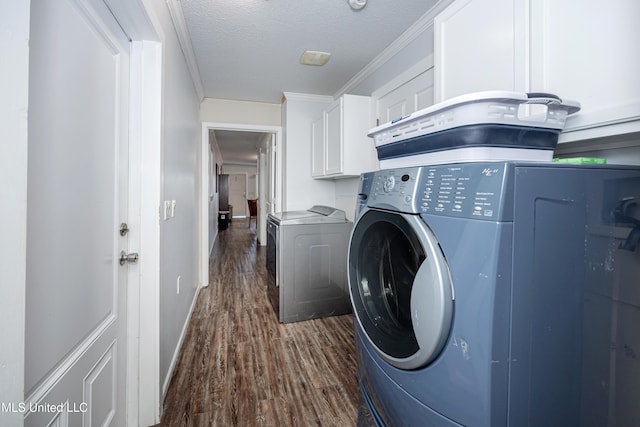 clothes washing area with a textured ceiling, cabinets, dark hardwood / wood-style floors, ornamental molding, and independent washer and dryer