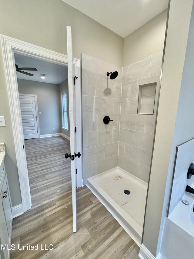 bathroom with hardwood / wood-style flooring, vanity, and tiled shower