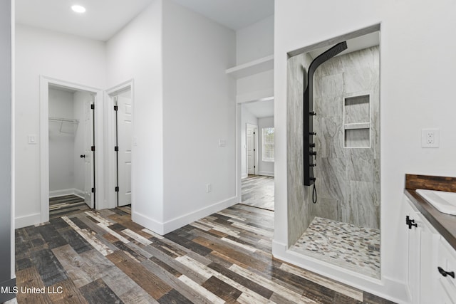 bathroom with a tile shower, hardwood / wood-style floors, and vanity