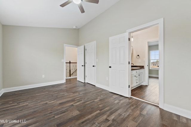 unfurnished bedroom featuring ceiling fan, dark wood-type flooring, ensuite bathroom, and lofted ceiling