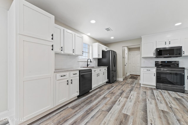 kitchen featuring light wood-type flooring, appliances with stainless steel finishes, sink, and white cabinetry