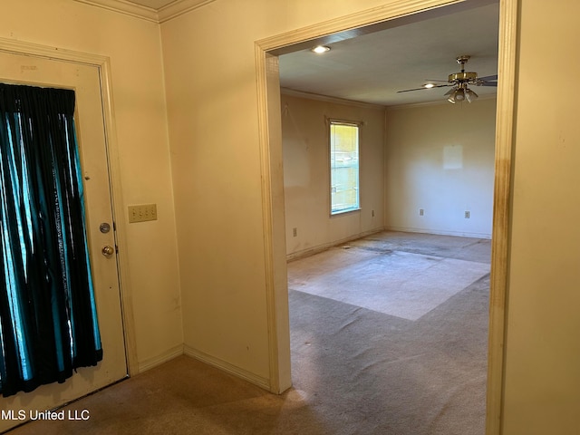 carpeted entrance foyer with crown molding and ceiling fan