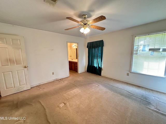 unfurnished bedroom featuring light carpet, ensuite bathroom, and ceiling fan