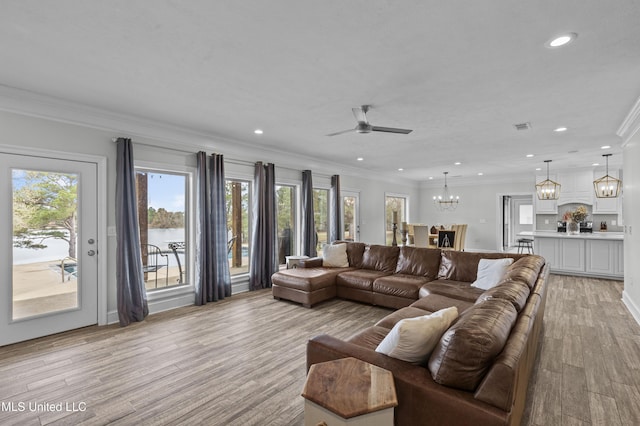 living room with recessed lighting, crown molding, light wood-style flooring, and ceiling fan with notable chandelier