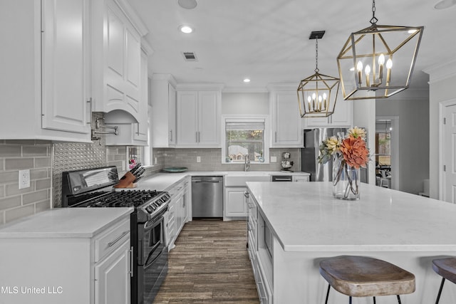 kitchen featuring appliances with stainless steel finishes, white cabinets, a sink, and ornamental molding