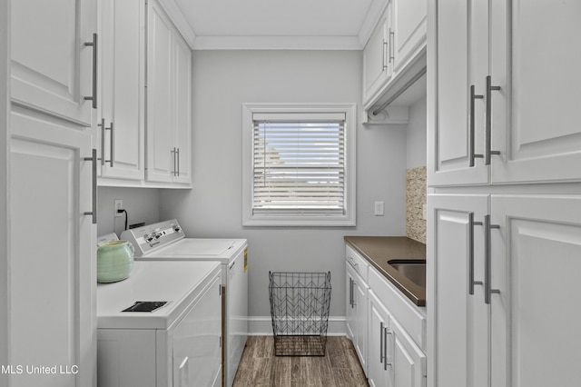 laundry area with dark wood-type flooring, baseboards, washer and dryer, cabinet space, and crown molding