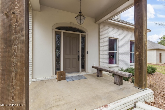 entrance to property featuring brick siding and stucco siding